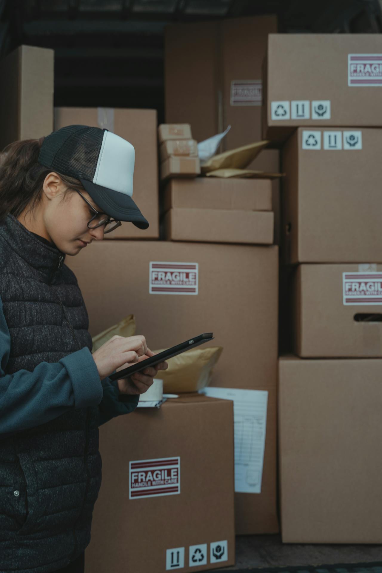 Woman checking orders on a tablet while standing in front of several boxes